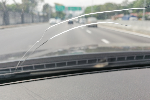 Perspective view of cracked car windscreen or windshield from inside vehicle while driving