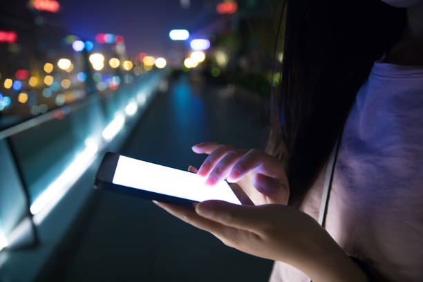 istock Hand holding mobile phone at night street 687679408