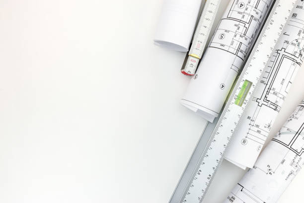 istock rolls of architectural blueprints, spirit level, zigzag ruler on white background 687679658