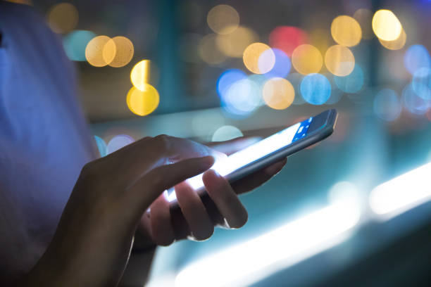 istock Hand holding mobile phone at night street 687680350