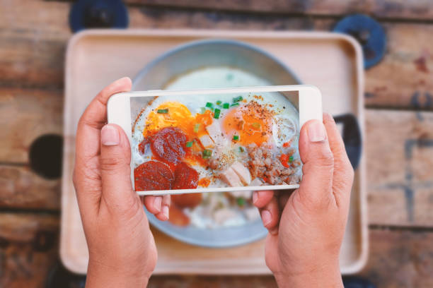 istock Top View of man using smartphone take pan fried egg photo on the table 687684980