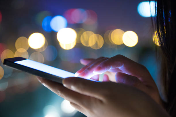 istock Hand holding mobile phone at night street 687685370
