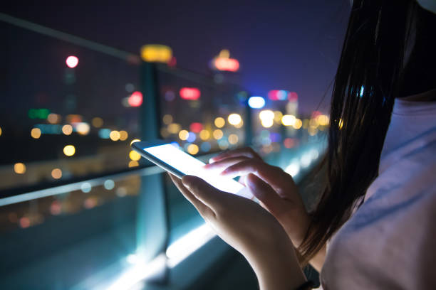 istock Hand holding mobile phone at night street 687685450