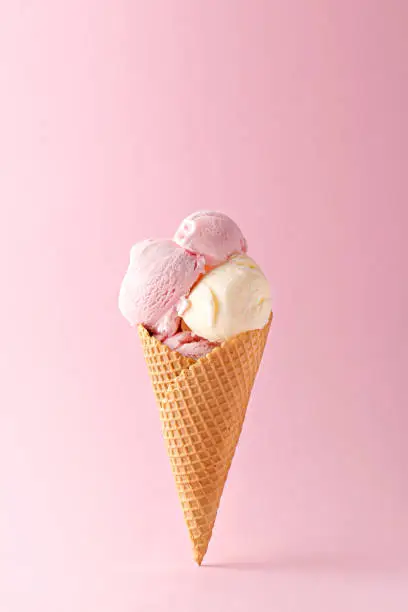 Ice cream cone vanilla and strawberry flavors on a pink background. Copy space