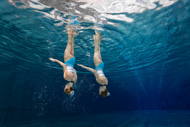 las mujeres en el deporte, las adolescentes bajo el agua sincronizan natación - symmetry fotografías e imágenes de stock