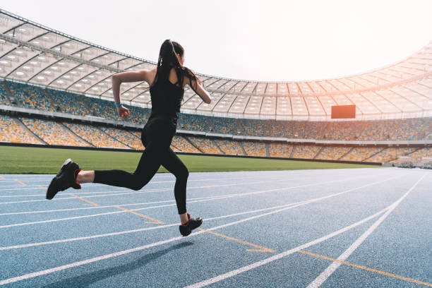 atletyczna młoda kobieta w odzieży sportowej sprint na stadionie na torze o zachodzie słońca - stadium empty seat women zdjęcia i obrazy z banku zdjęć