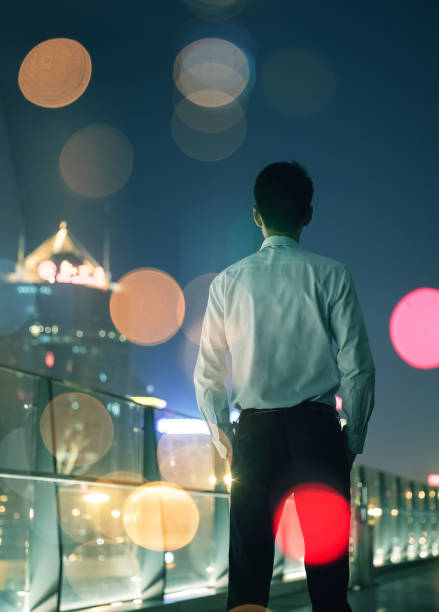istock Businessman looking at city at night 687689618