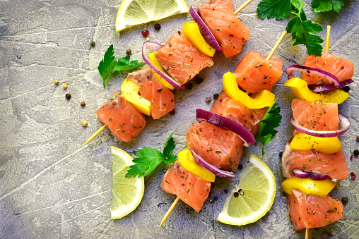 Raw salmon kebab on a grey slate,stone or concrete background.Top view .