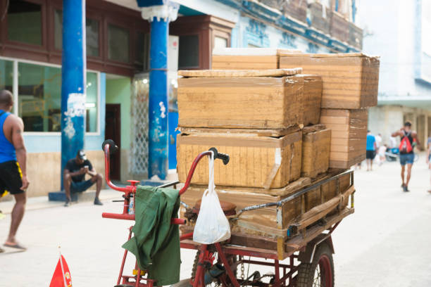A bicycle loaded with packages to be delivered is parked in a busy pedestrian zone in Havana, Cuba. People walk in the background. Photographed with a Nikon D800 DSLR camera.