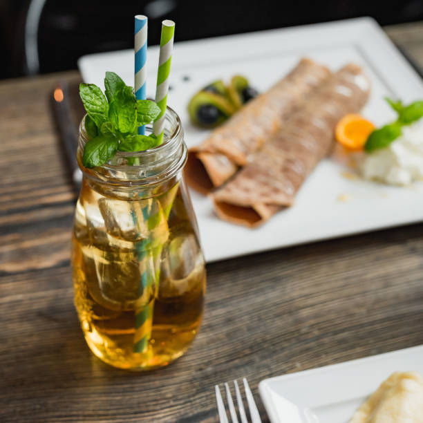 Glass of juice with ice and straw od wooden table.