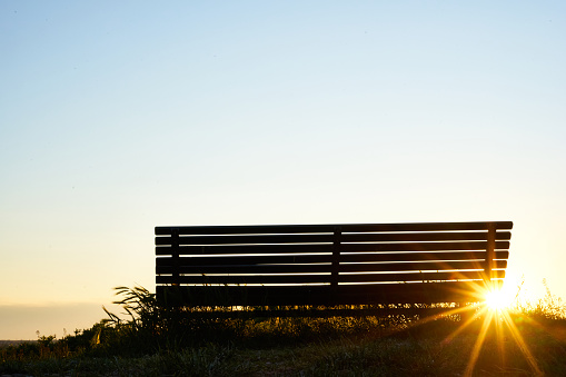 Lonely bench at sunset with sunrays