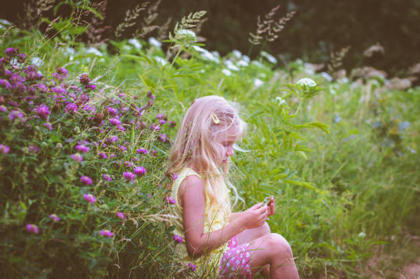 istock little blond girl sitting in the grass 687715220