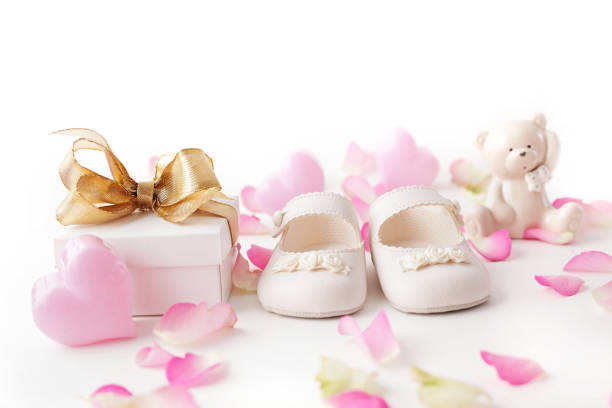 close-up of baby shoes, gift box and rose petals