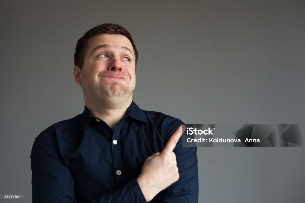 Surprised man showing on important information The man barely holds back from laughing and points with his index finger at interesting information Laughing Stock Photo