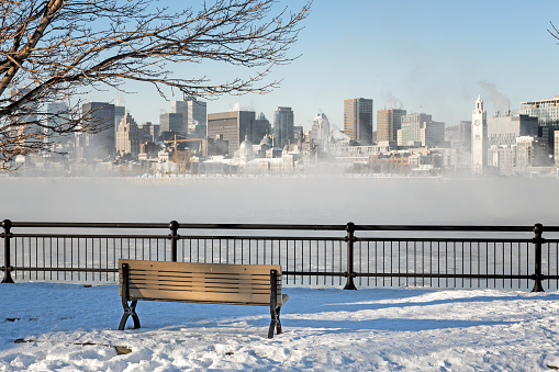 A view across the St Lawrence river to downtown Montreal. Winter shot with snow on the ground and mist rising from the frozen water.