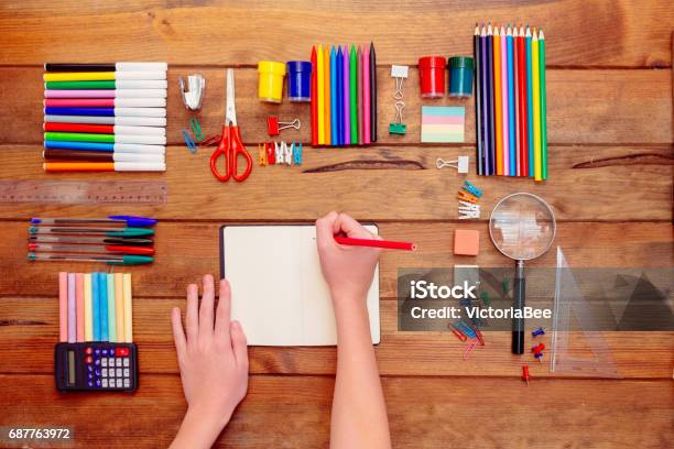 Tangan Anakanak Menulis Di Buku Catatan Berbagai Perlengkapan Sekolah Flat Lay Copy Space Studio Ditembak Di Latar Belakang Kayu Foto Stok - Unduh Gambar Sekarang