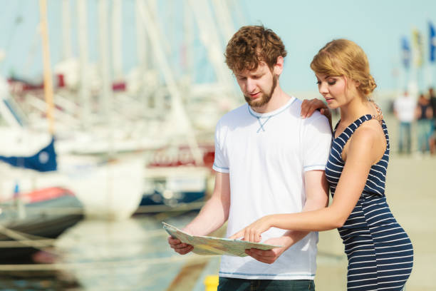 istock Tourist couple in marina looking up directions on map 687764012
