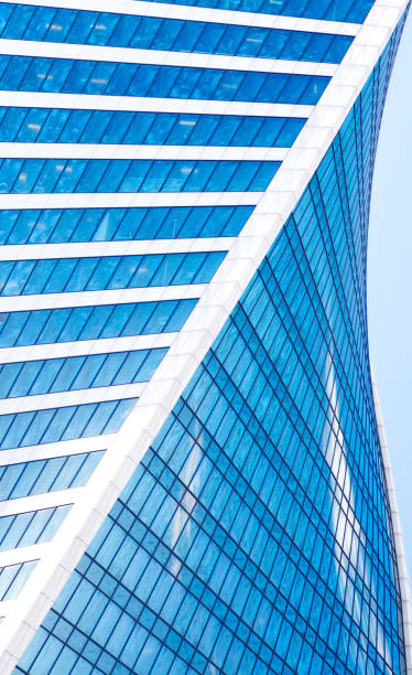 Abstract skyscrapers with reflection in windows blue sky, white clouds and sun glare