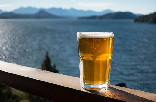 A glass of beer on deck rail overlooking Lake Huapi , Bariloche.