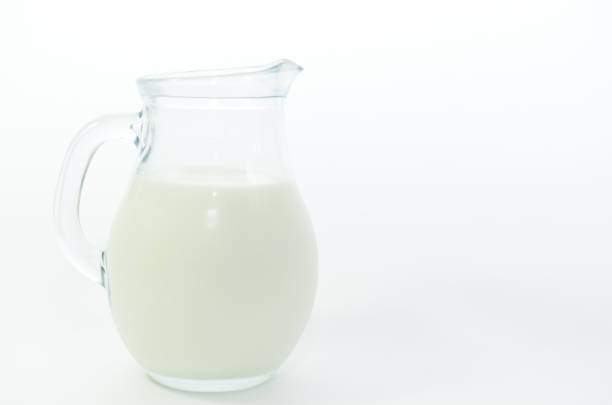 Fresh cow milk in a jar on a light background.