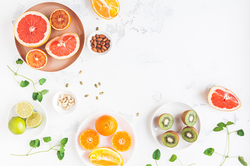 Colorful fresh fruit on white table. Orange, tangerine, lime, kiwi, grapefruit. Summer fruit. Flat lay, top view, copy space