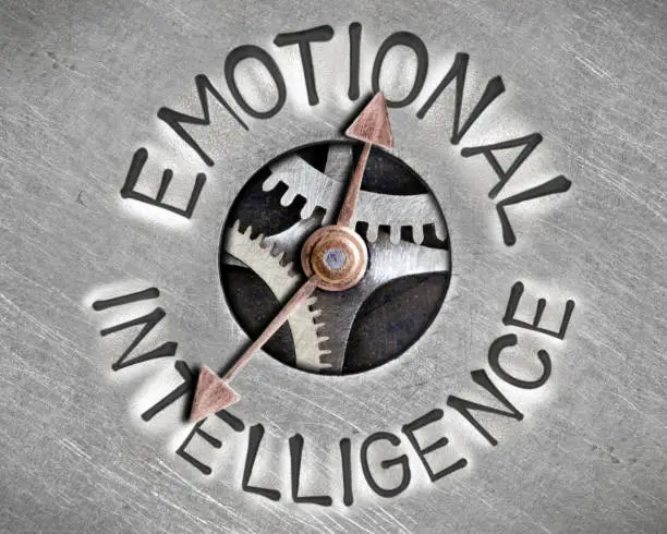 Macro photo of pointer and tooth wheel mechanism with EMOTIONAL INTELLIGENCE letters imprinted on metal surface