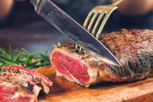 Cutting Juicy Beef Steak Young women cutting medium roasted beef steak on the wooden board carving food photos stock pictures, royalty-free photos & images