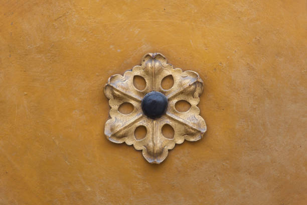 Decorative gilded metal floral rosette on the yellow ochre background.