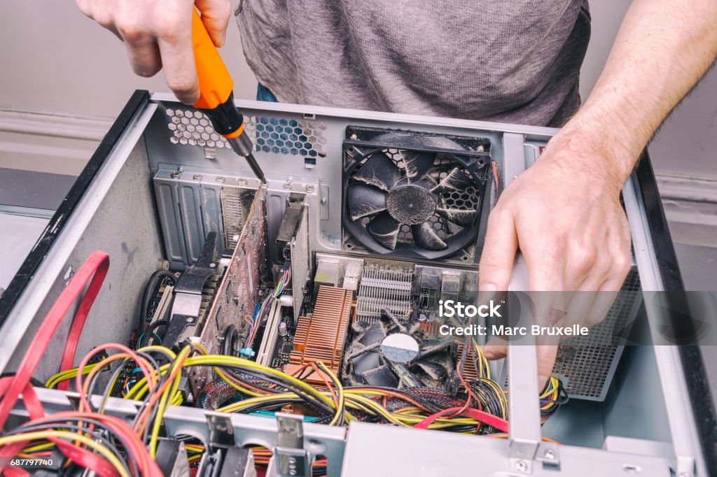 Man fixing an old desktop computer using a screwdriver Repairing Stock Photo