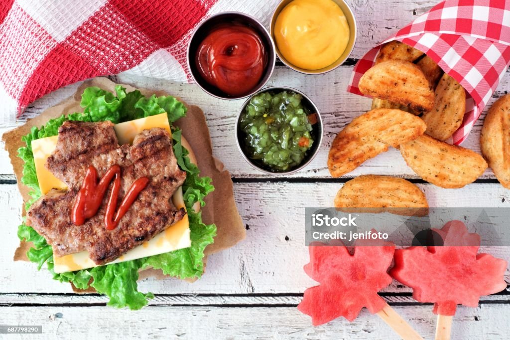 Canada Day picnic scene with maple leaf hamburger and watermelon Canada Day picnic scene with maple leaf shaped hamburger, watermelon pops and potato wedges Canada Day Stock Photo