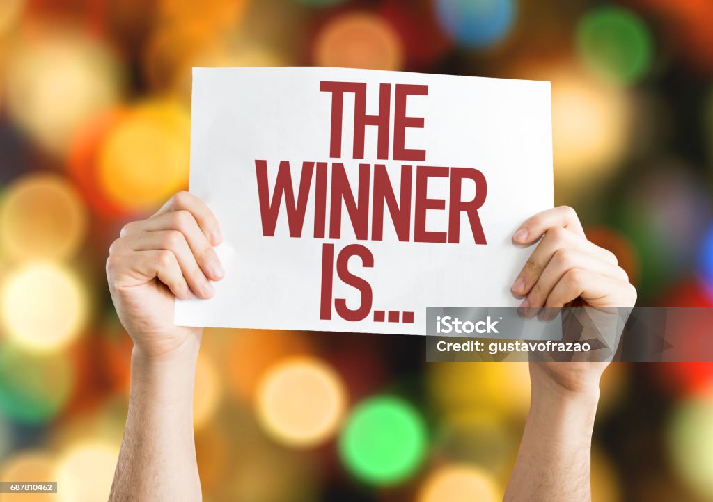 The Winner Is... placard The Winner Is... placard with bokeh background Winning Stock Photo