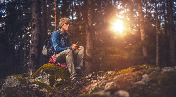 istock Young woman using a smartphone in the forest 687810596
