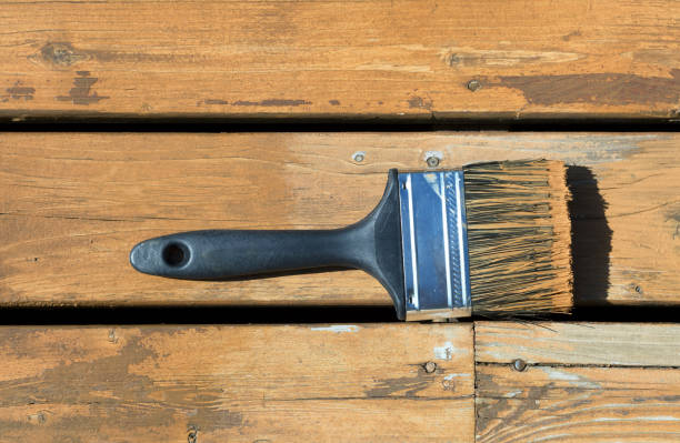 istock Used paintbrush filled with wood stain on a natural cedar deck 687813722