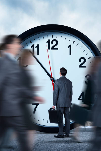 istock Businessman Looking At Clock As Others Pass Him By 687824680