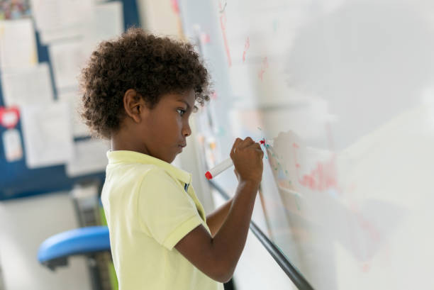 African American boy at the school writing on the board Portrait of an African American boy at the school writing on the board - education concepts kids using smart board stock pictures, royalty-free photos & images