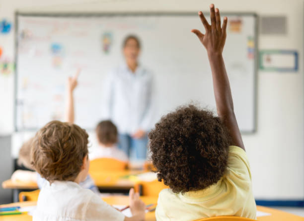 istock Kids raising their hands in class at the school 687830466