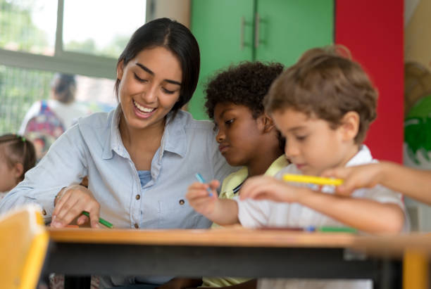 istock Happy teacher talking to young students at the school 687830502