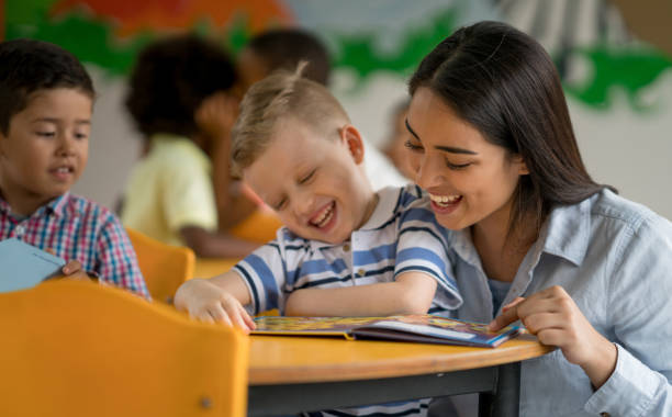 istock Happy boy at the school reading a book with his teacher 687830686