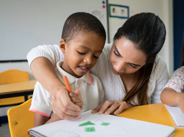 istock Teacher supervising a boy drawing at the school 687830720
