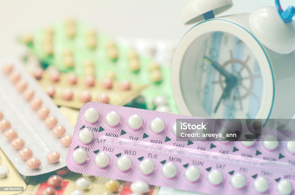 Pillules contraceptives orales avec le fond de réveil dans le rappel de temps pour prendre des pillules. - Photo de Contraceptif libre de droits