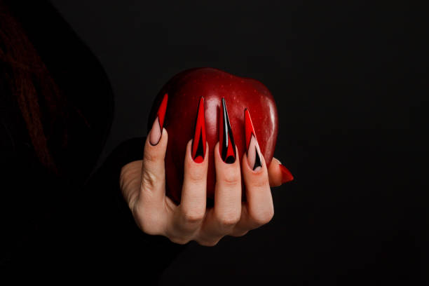 Hands with scary nails manicure holding poisoned red apple Hands with scary nails manicure holding poisoned red apple , isolated on black background woman claw hand stock pictures, royalty-free photos & images