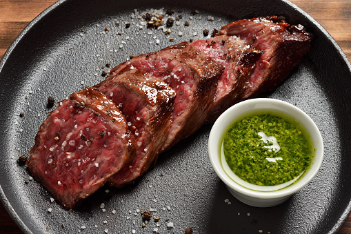 Prime Black Angus Skirt steak with sauce in a pan. Medium Rare degree of steak doneness.