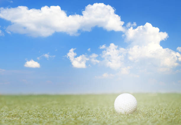 istock golf ball on fake green grass with sunlight and cloud blue sky background. 687853596