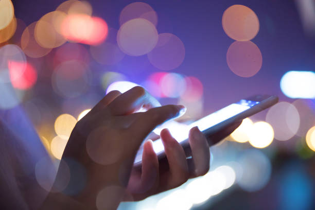 istock Hand holding mobile phone at night street 687854160