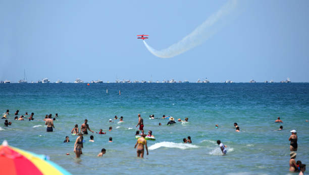 Fort Lauderdale, Florida, USA, May 7, 2017:  Fort Lauderdale beachgoers play in the Atlantic Ocean and watch the Fort Lauderdale Air Show planes perform their stunts.