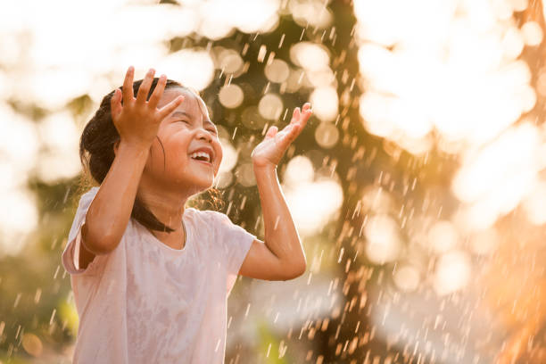 Happy asian little girl having fun to play with the rain Happy asian little girl having fun to play with the rain in vintage color tone raining outside stock pictures, royalty-free photos & images