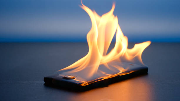 Smartphone lies and burning on a table in the night Smartphone lies and burning on a table in the night overheated photos stock pictures, royalty-free photos & images