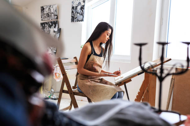 istock Prifile view of female painter working in her studio 687893000