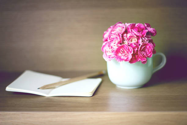 istock selective focus of Fresh pink carnation flower with note book on wooden shelf background 687912082