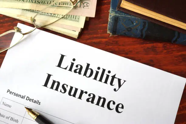 Photo of Liability insurance on a wooden table with glasses.